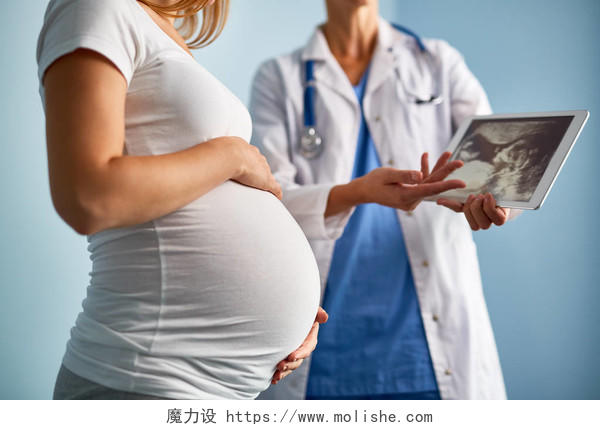 女医生向孕妇使用数字平板解释超声扫描结果摄影图